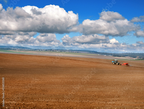 panoramic view of plowed field, tractor with seeder, beautiful sky with clouds. agricultural land, it is time to sow