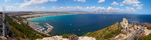 Views of an island from the top with a harbor, a beach with turquoise water,, salt fields and a town in Sardinia