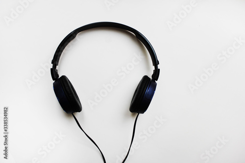 On-ear headphones isolated on light grey background. Black color old wired over-ear headphones, music listening device close up top view with empty copy space for text and advertising