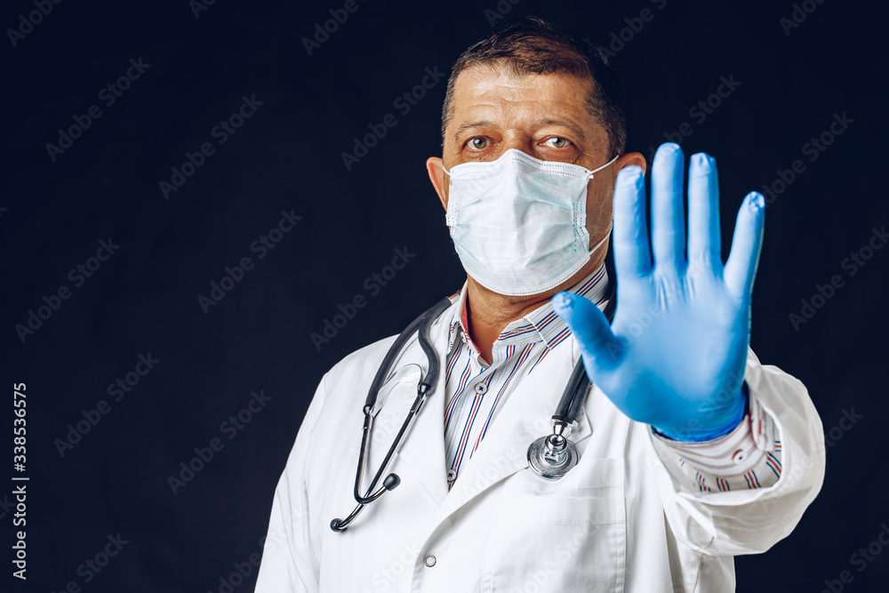 Male Doctor Showing Stop Sign. Doctor Wearing Medical Mask and Gloves. Close up. Male Doctor Showing Stop Sign. Doctor Wearing Medical Mask and Gloves. Close up.