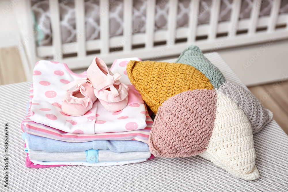 Baby clothes with booties and pillow on table in room Baby clothes with booties and pillow on table in room