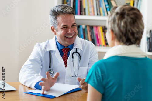 Laughing mature doctor talking about recovery to patient