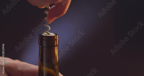 man with a corkscrew opens a bottle of wine on a black background