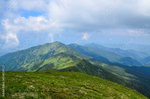 View to a chain of green mountains peaks on cloudy summer day. gorgeous landscape of Carpathian mountains Marmarosy ridge. Trekking in mountains.