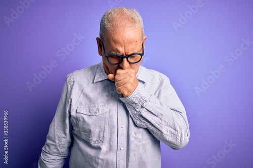 Middle age handsome hoary man wearing striped shirt and glasses over purple background feeling unwell and coughing as symptom for cold or bronchitis. Health care concept.