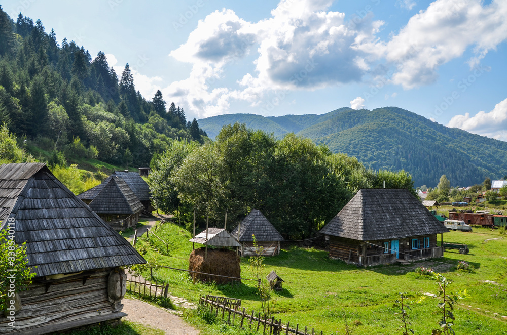 Rural landscape with ancient wooden houses on a green hill in the mountain village Kolochava, Transcarpathia, Ukraine