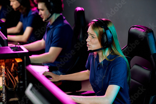 Worried E-sport girl in headset with microphone playing video game in computer club