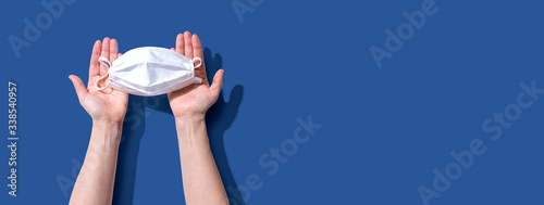 Person holding a white surgical mask overhead view - flat lay