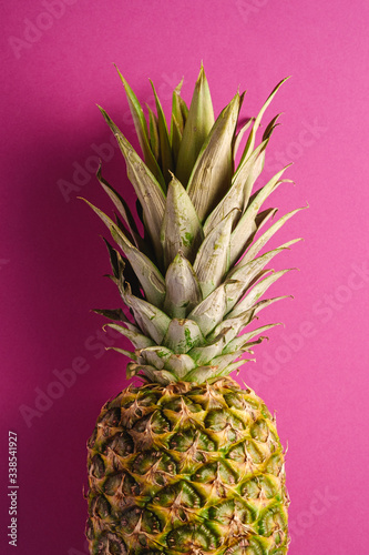 Fresh sweet pineapple on pink purple background, top view, cropped