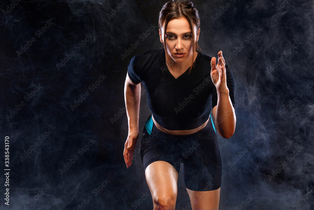 Obraz premium Sprinter and runner girl. Running concept. Woman running on the black background. The concept of a healthy lifestyle and sport. Woman in sportswear.