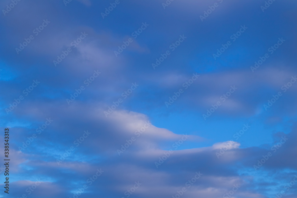 blue sky with torn clouds in places
