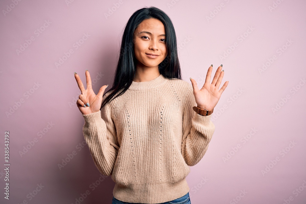 Young beautiful chinese woman wearing casual sweater over isolated pink background showing and pointing up with fingers number eight while smiling confident and happy.