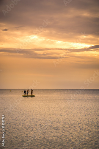 three personns on a sea platform on new caledonia sunset. portrait format
