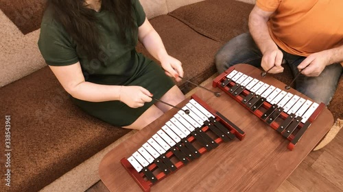 A man and a woman at home playing on metal phones in the living room photo