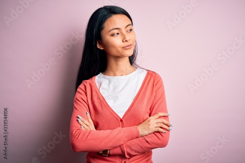 Young beautiful chinese woman wearing casual sweater over isolated pink background looking to the side with arms crossed convinced and confident © Krakenimages.com