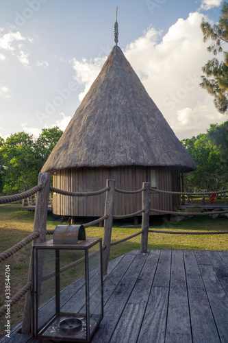 typical kanak hut. Candle light put on a wood pation in the foreground photo