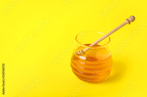 Jar of sweet honey on color background