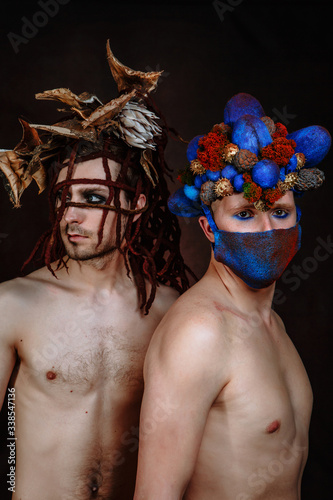 Two male models. A model with an egg - shaped headdress of cones and a mask on her face. Model with a headdress made of tree bark and ropes photo