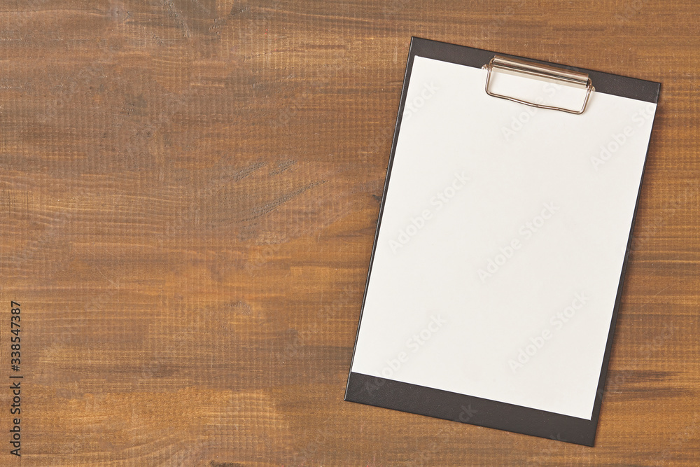 Clipboard with a blank sheet of paper on wooden table with copy space