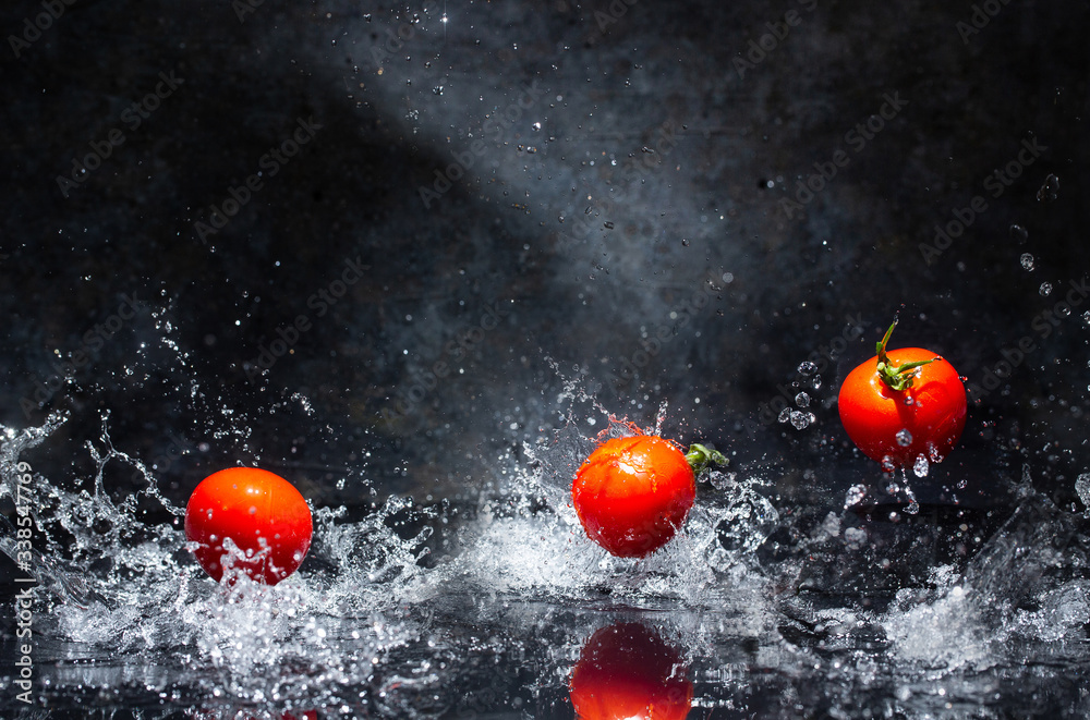 flying red tomatoes in water drops on a gray background