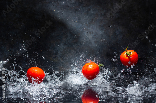 Obraz na płótnie flying red tomatoes in water drops on a gray background w salonie