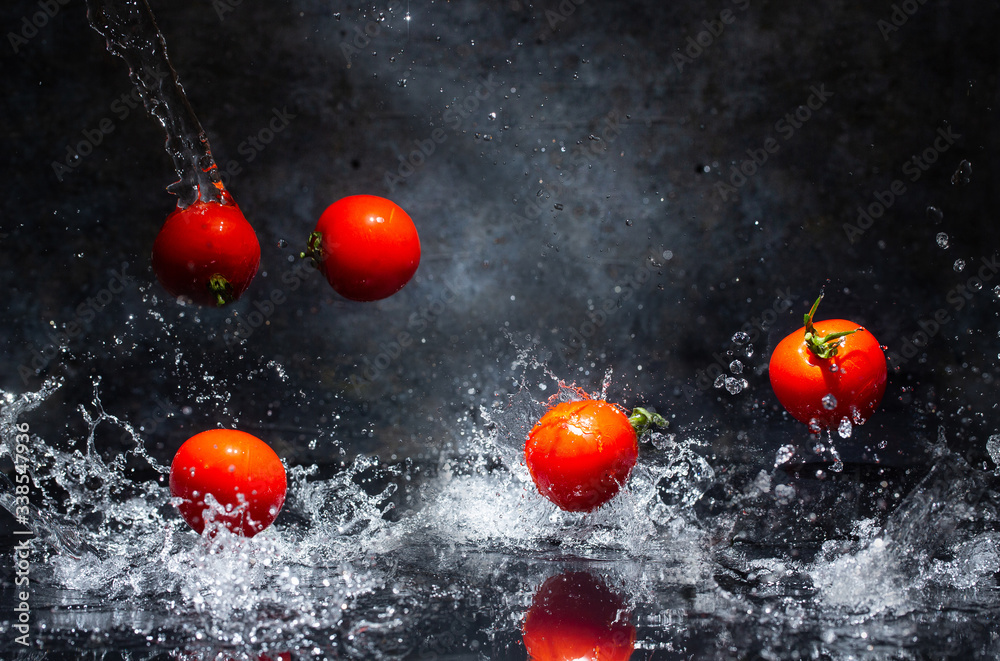 flying red tomatoes in water drops on a gray background
