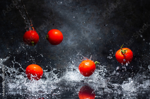 Obraz na płótnie flying red tomatoes in water drops on a gray background w salonie