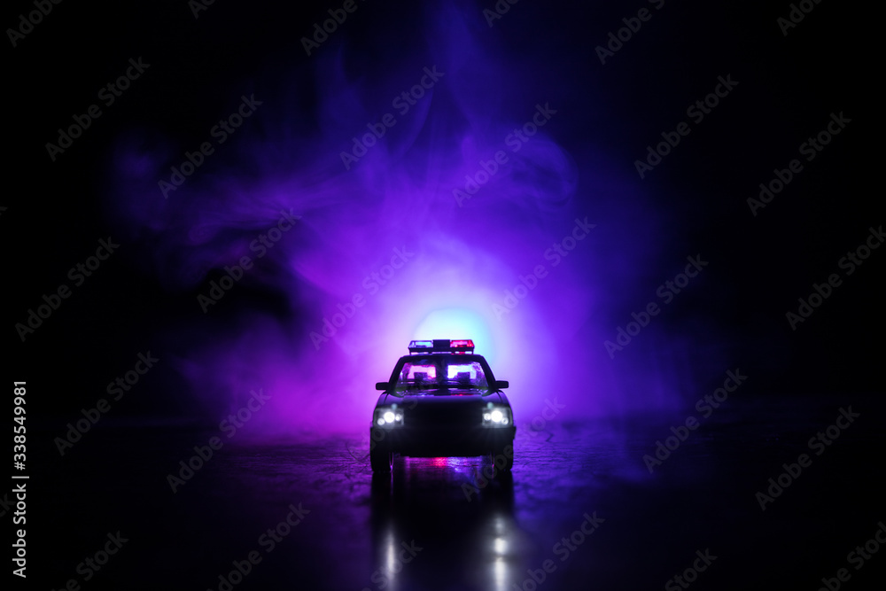 Police cars at night. Police car chasing a car at night with fog background. 911 Emergency response police car speeding to scene of crime. Selective focus Police cars at night. Police car chasing a car at night with fog background. 911 Emergency response police car speeding to scene of crime. Selective focus