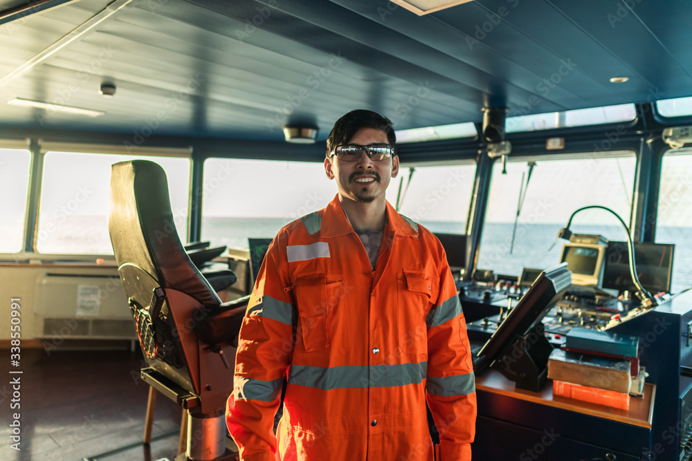 Filipino deck Officer on bridge of vessel or ship wearing coverall during navigaton watch at sea. - obrazy, fototapety, plakaty 