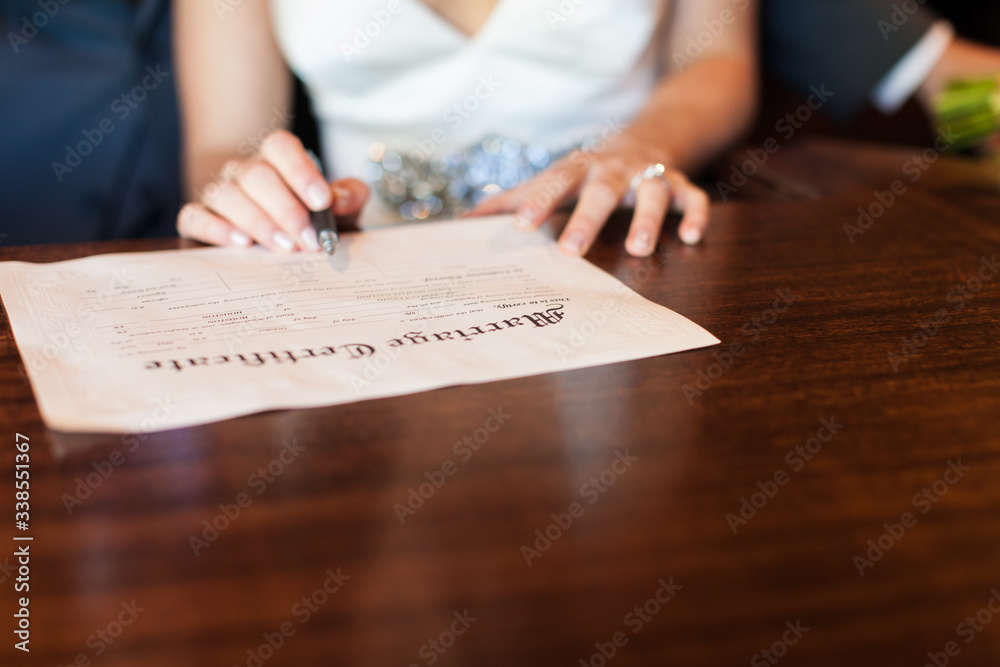 Bride holding pen signing marriage certificate Bride holding pen signing marriage certificate