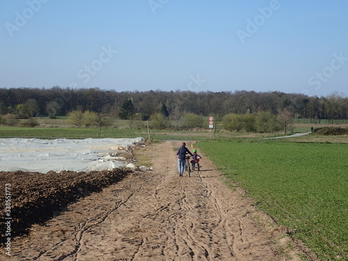 sandiger Weg zwischen umgegrabenen Feldern und Spargel-Folien