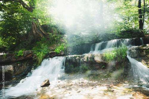 Atmospheric magical waterfall in deep wild green forest in Carpathian mountains