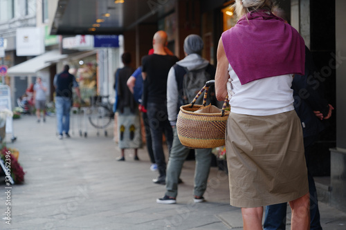 Schilderij op canvas Low angle and selected focus, European people queue and wait for shopping on sidewalk outside supermarket during quarantine for COVID-19 virus in Düsseldorf, Germany