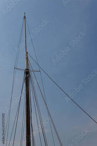 Mast and rigging of an old sailing vessel, ships and boats, blue sky, vertical aspect