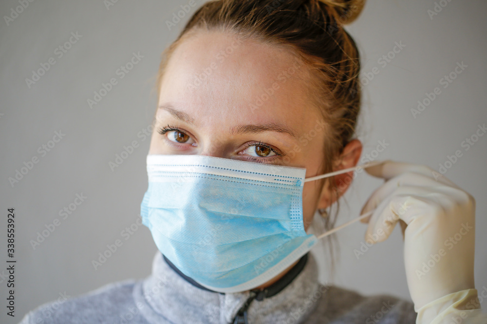 The young woman's first-line doctor uses a protective mask, she has white sterile gloves on hand. The young woman's first-line doctor uses a protective mask, she has white sterile gloves on hand.