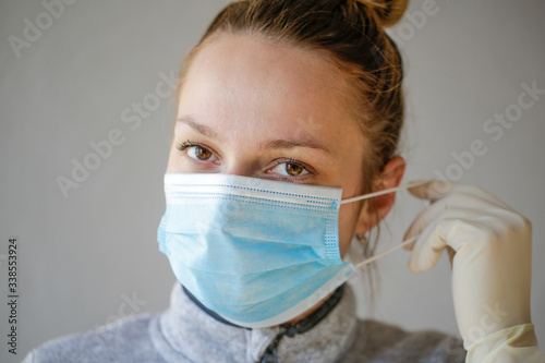 The young woman's first-line doctor uses a protective mask, she has white sterile gloves on hand.