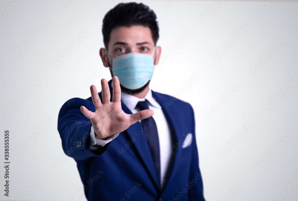 Young man with blue suit showing stop sign with hand, wearing medical face mask. stop coronavirus concept. Young man with blue suit showing stop sign with hand, wearing medical face mask. stop coronavirus concept.