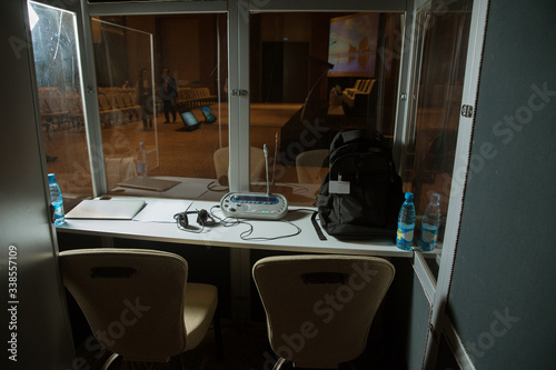 Soft focus of wireless Conference microphones and notebook in a meeting room. translators cubicle . interpreting - Microphone and switchboard in an simultaneous interpreter booth .