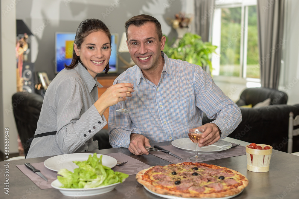 Young italian couple ready to share  a pizza and a glass of rose wine