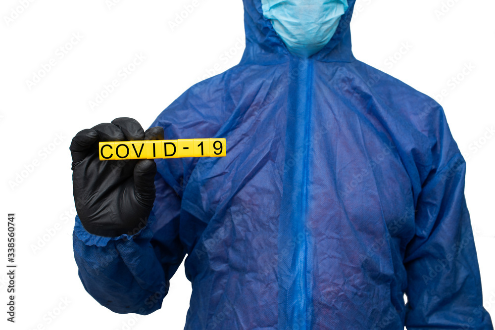 a man in a protective suit and mask holds a sign that reads covid 19