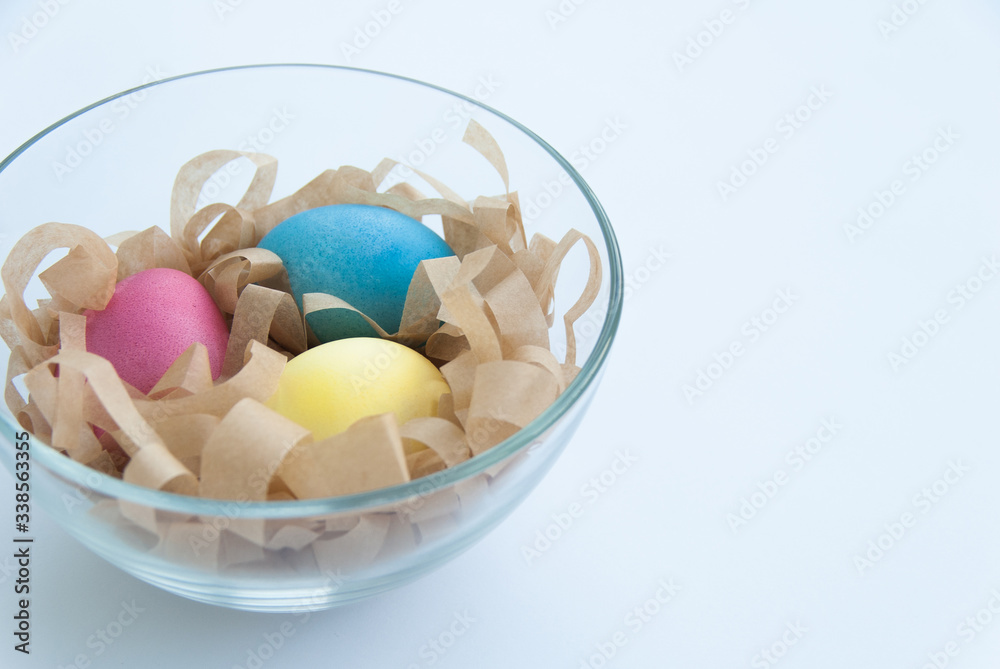 Colourful Easter eggs on a hay in a glass bowl. Isolated on white background. Close up Colourful Easter eggs on a hay in a glass bowl. Isolated on white background. Close up
