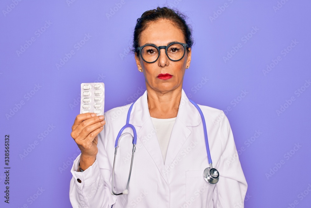 Middle age senior professional doctor woman holding pharmaceutical pills with a confident expression on smart face thinking serious Middle age senior professional doctor woman holding pharmaceutical pills with a confident expression on smart face thinking serious