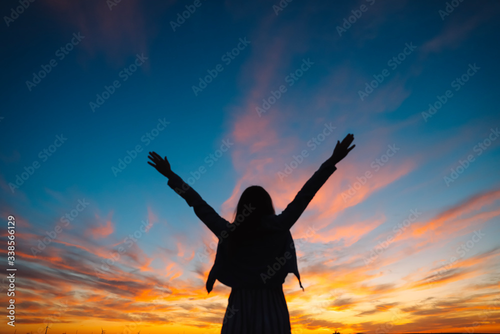 Woman open arms under the sunset. Concept of happy life, freedom.