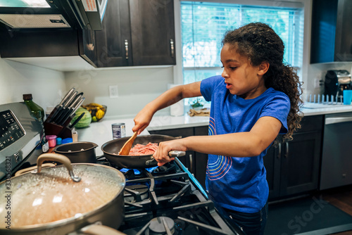 Girl cooking meal at stove in home kitchen
