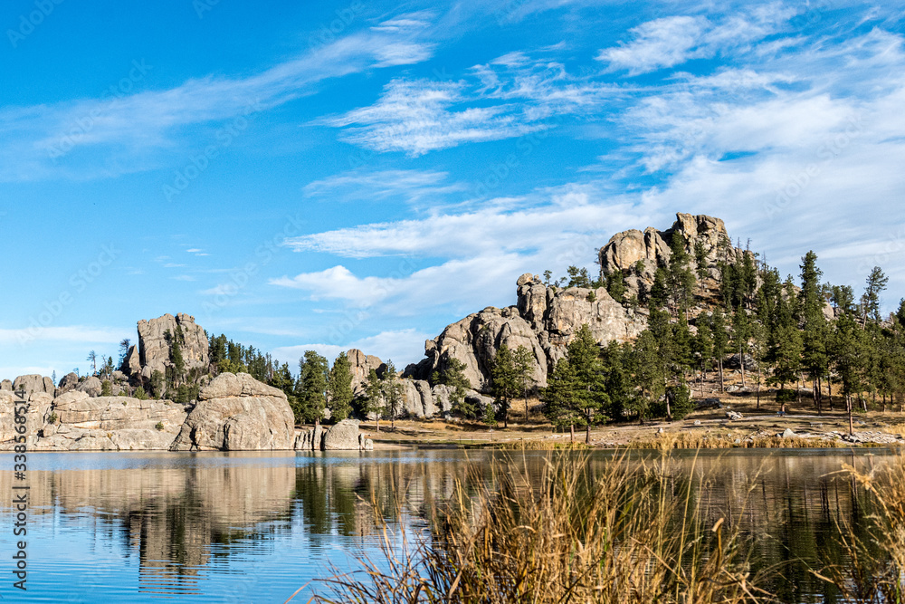 Rock Formation And Evergreen Trees Next To Lake