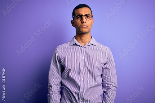 Handsome african american man wearing striped shirt and glasses over purple background depressed and worry for distress, crying angry and afraid. Sad expression.