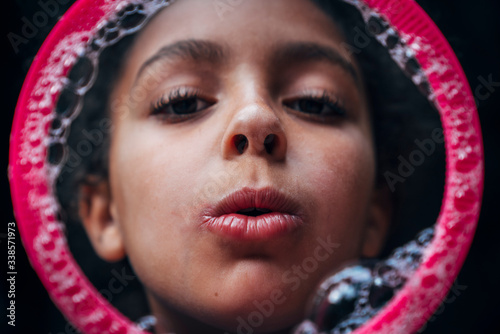 Close-up shot of girl blowing bubble through giant wand