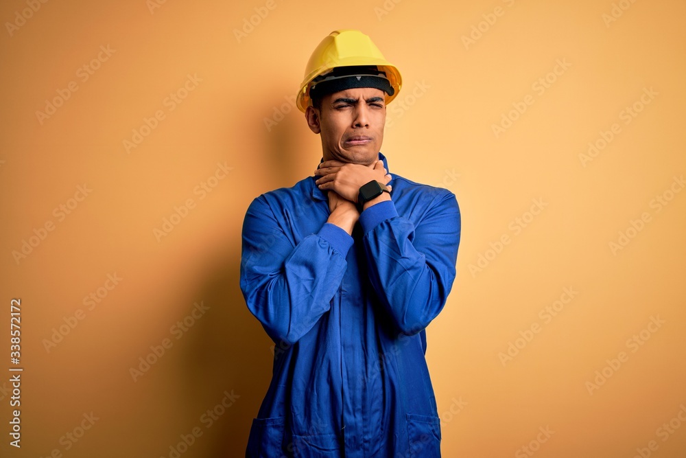 Young handsome african american worker man wearing blue uniform and security helmet shouting suffocate because painful strangle. Health problem. Asphyxiate and suicide concept.