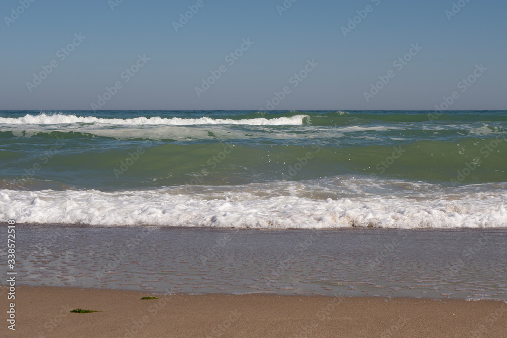 Sea, sea waves and shoreline on a sunny windy day.