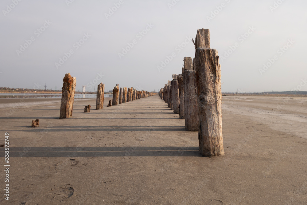 The remains of an old pier. Aged logs stick out of sand at the bottom of a dried reservoir. The remains of an old pier. Aged logs stick out of sand at the bottom of a dried reservoir.